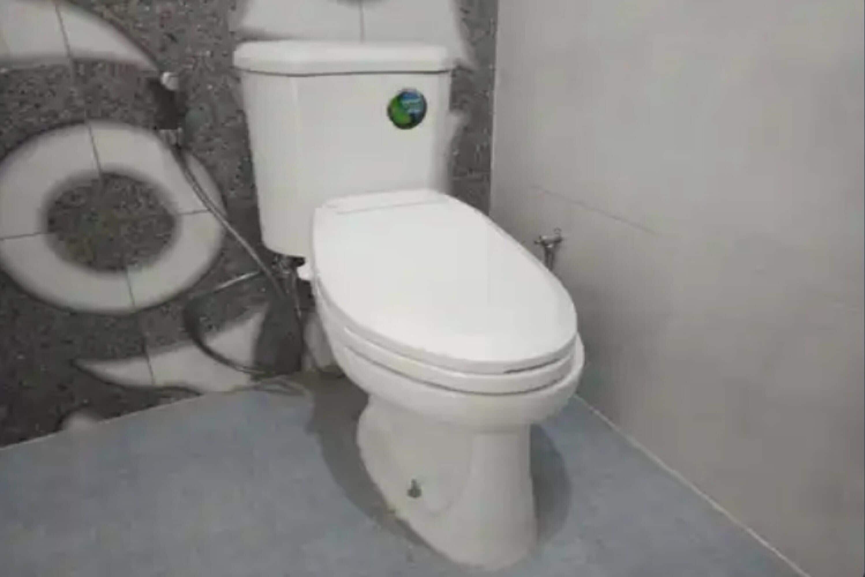 A bathroom with a toilet, a toilet paper holder, and a wall-mounted toilet paper dispenser.