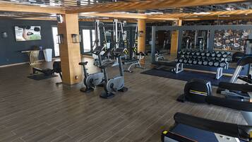 A gym with various exercise equipment, including treadmills, stationary bikes, and weight machines.