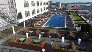 A rooftop pool area with lounge chairs and a swimming pool. - Yogh Hospitality (Paramaribo)