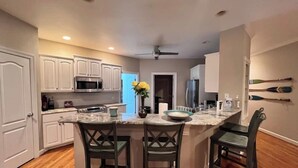 A modern kitchen with white cabinets, a marble countertop, and a central island with bar stools. - Modern Lakefront Retreat - 3br 2ba (Sanford)
