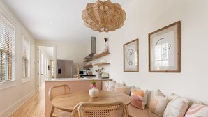 A modern kitchen with wooden cabinetry, a central island, and a dining area with a round table and chairs. - Charming 5 Bedroom House - 1 Block to King Street (Charleston)