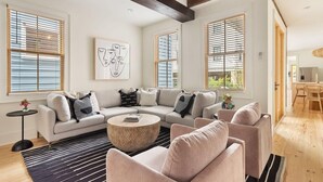 A modern living room with a sectional sofa, a round coffee table, and a large abstract painting. - Charming 5 Bedroom House - 1 Block to King Street (Charleston)