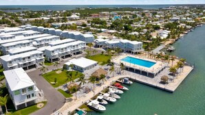 A resort with multiple white buildings, a swimming pool, and a marina with boats. - Oceanfront Gated Community / Heated Pool (Marathon)