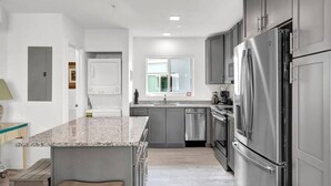 A modern kitchen with stainless steel appliances, a granite countertop, and a large island. - Oceanfront Gated Community / Heated Pool (Marathon)