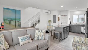 A modern kitchen with a central island, a dining area with a bench, and a living room with a sofa and cushions. - Oceanfront Gated Community / Heated Pool (Marathon)