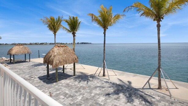 A beachside deck with thatched umbrellas and palm trees, overlooking the sea. - Oceanfront Gated Community / Heated Pool (Marathon)