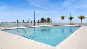A rectangular swimming pool with clear blue water, surrounded by a white deck and palm trees. - Oceanfront Gated Community / Heated Pool (Marathon)