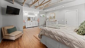 A bedroom with a bed, a TV, a dresser, and a chair. - Secluded Coastal Retreat | Walk to Beach (Cocoa Beach)