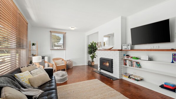 A modern living room with a fireplace, a flat-screen TV, and a bookshelf. - Surfside - Point Lonsdale (Point Lonsdale)