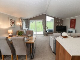 A spacious living area with a dining table, sofas, and a TV.
