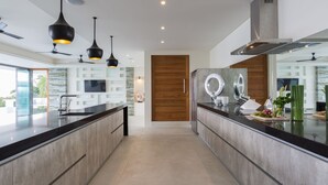 A modern kitchen with a central island, pendant lighting, and a large window. - Spice : 3 Bed Sublime Luxury Five Star Villa (Koh Samui)