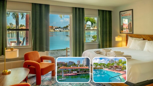 Ein Hotelzimmer mit Bett, Stuhl, Tisch und Blick auf einen Pool und Gebäude.
