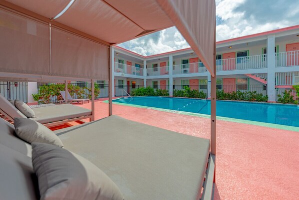 Un hôtel doté d’une piscine, de plusieurs balcons et d’un espace salon couvert.