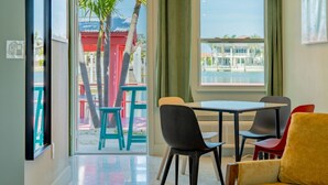 Una habitación con balcón, una mesa de comedor con sillas y un sofá.