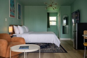 Una habitación con una cama, un escritorio, una silla, una lámpara, un televisor y un refrigerador.