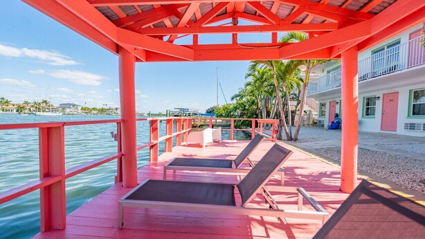 Una terraza de madera roja con sillones de descanso con vista a un puerto deportivo.