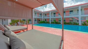 A hotel with a pool area, multiple balconies, and a covered seating area.