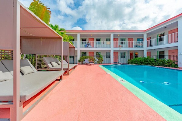 A hotel with a swimming pool, multiple balconies, and outdoor seating areas. - Bay View Studio with Two Beds and Balcony (Clearwater)