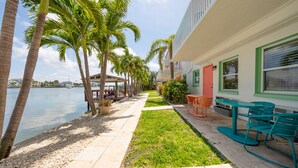 A waterfront property with a patio, outdoor seating, and palm trees.