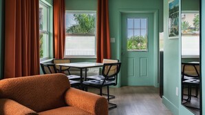 A room with a dining table, chairs, a sofa, and a door with a window. - 2201 · 3 Min Walk -> Beach / Heated Pool / Free Parking (Clearwater)