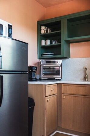 Una cocina con un refrigerador de acero inoxidable, un horno empotrado y una cafetera.