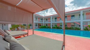Un hôtel doté d’un espace piscine comprenant des chaises longues et un coin salon abrité.
