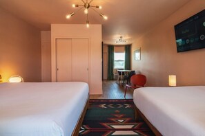 Habitación de hotel con dos camas, zona de comedor y televisor mostrando la aplicación de Hulu.