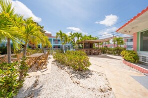 A resort courtyard with outdoor seating, palm trees, and a covered area.