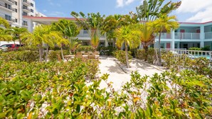 Une cour d’hôtel avec une piscine, des palmiers et un bâtiment doté de balcons.