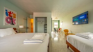 Une chambre d’hôtel avec deux lits, un bureau, une chaise et un téléviseur affichant la chaîne « max ».