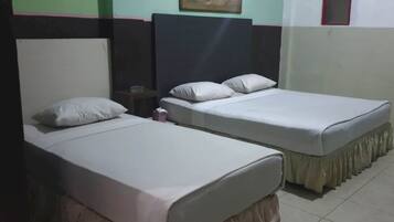 Two single beds with white linens and headboards, a small bedside table with a lamp, and a framed picture on the wall.