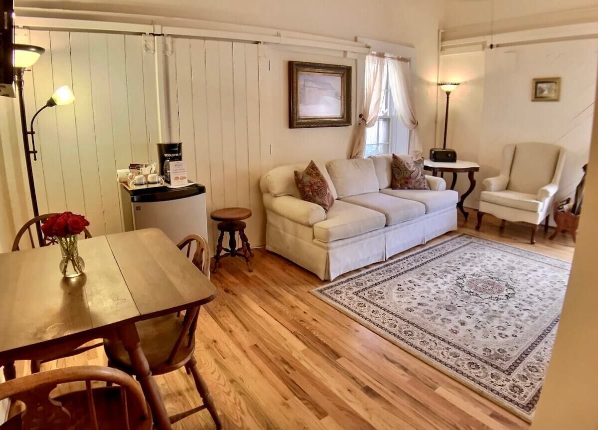 Una sala de estar acogedora con una mesa de comedor de madera, un sofá, una estación de café y un tapete estampado.