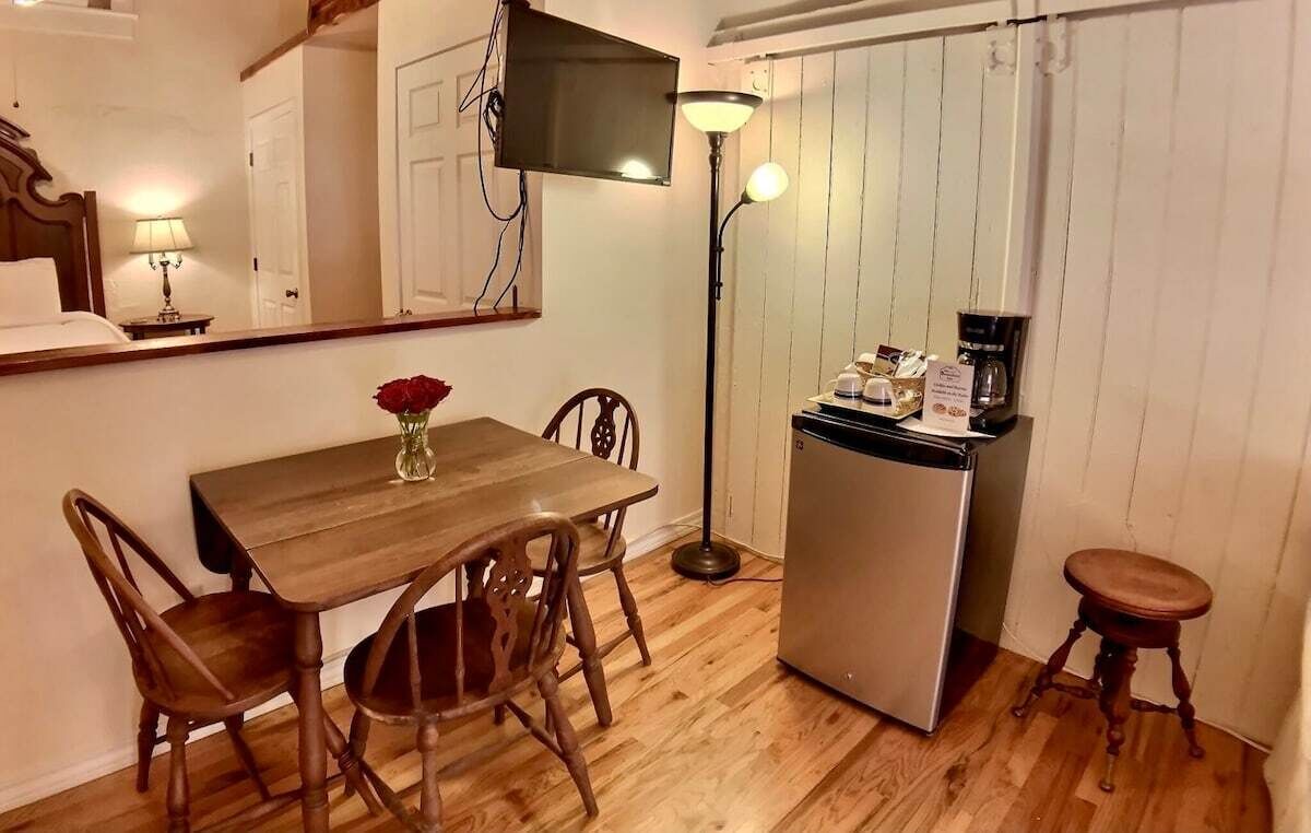 Une cuisine compacte équipée d’un réfrigérateur, d’une machine à café et d’une table à manger avec des chaises.