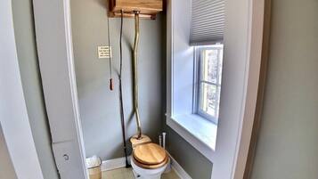 Un bagno piccolo con il water, una finestra e un armadietto in legno sopra il water.