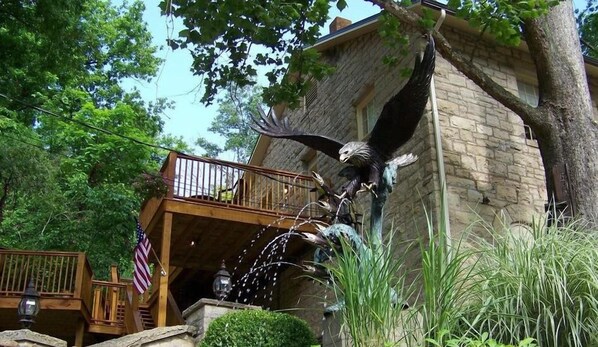 A bird perched on a stone structure with a wooden deck and an American flag. - Walkable Historic Downtown| Coffee | Parking (Eureka Springs)