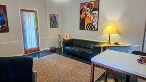 A living room with a black sofa, a wooden coffee table, a lamp, and artwork on the walls. - The Moderne Suite Downtown Balcony, Parking (Eureka Springs)