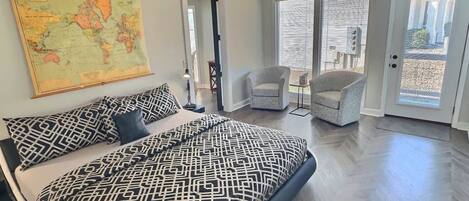 A bedroom with a large bed, a world map on the wall, and a view to the outside.