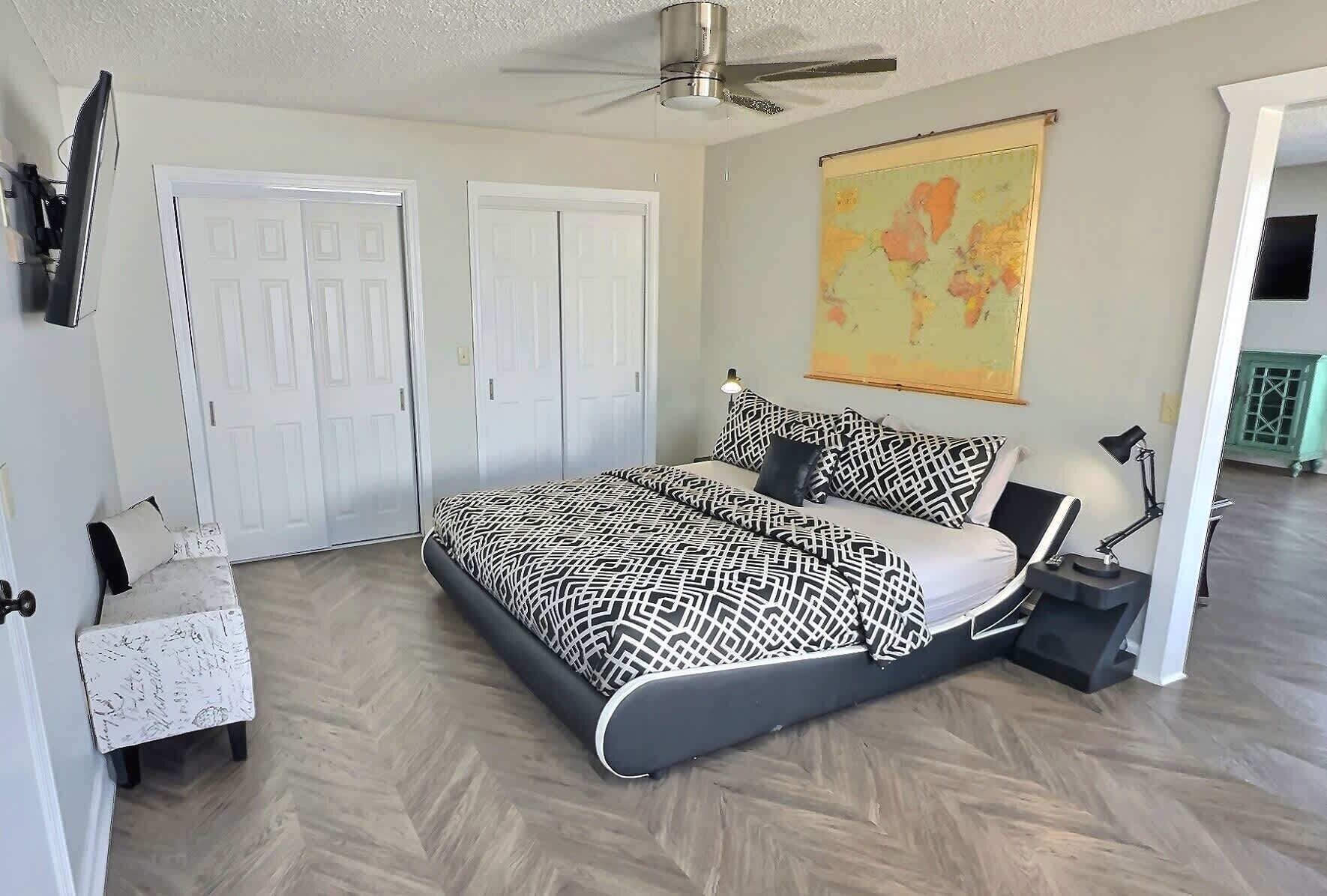 Une chambre avec un lit, un bureau, une chaise et une carte accrochée au mur.