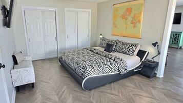 A bedroom with a bed, a desk, a chair, and a map on the wall.