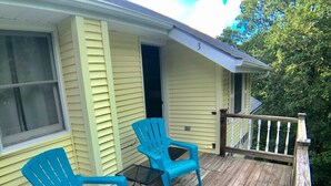 Eine Veranda mit zwei blauen Adirondack-Stühlen, einem kleinen Tisch, einem Holzboden und einem weißen Geländer.
