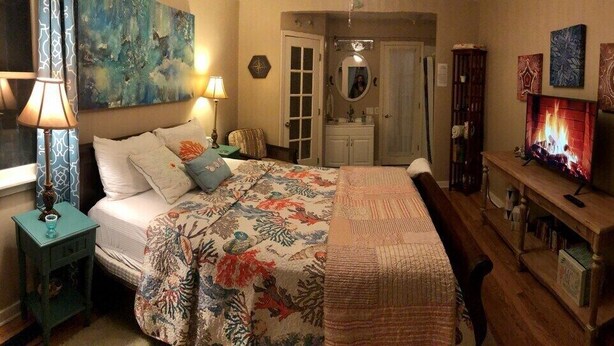 A bedroom with a bed, bedside tables, a TV, and a fireplace.