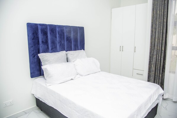 Cozy retreat with a large bed, white wardrobe, and marble floor.