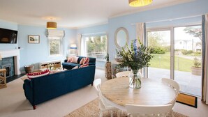 A spacious living room with a blue sofa, a round wooden table, and a fireplace. - Beautiful 5-bed House in Port Isaac (Port Isaac)