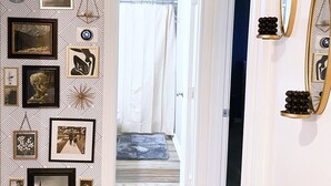 A hallway with a patterned wall, framed pictures, and a mirror. - Serenity Stay - 3BR 2BA - South Lubbock (Lubbock)