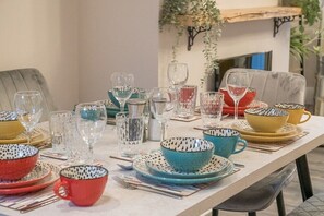 Una mesa de comedor dispuesta con diferentes vasos, y coloridos cuencos y platos.
