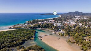 An aerial view of a coastal town with a beach, a bridge, and a dense forest area. - Aurora on Gregory Apartment (South West Rocks)