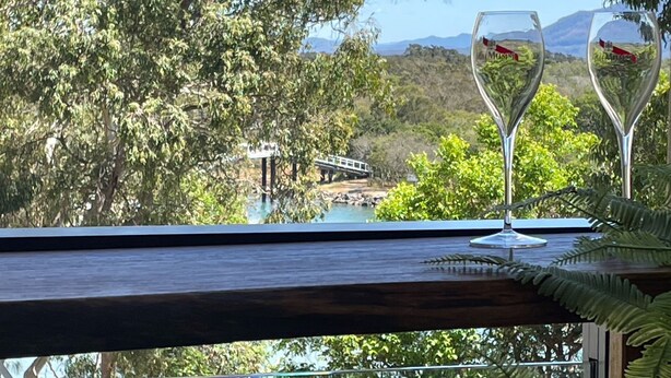 A view from a balcony overlooking a river, with a bridge and lush greenery in the background. - Aurora on Gregory Apartment (South West Rocks)