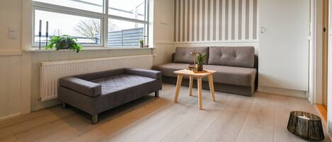Una sala de estar moderna con un sofá gris, una mesita de madera con una planta y un radiador debajo de una ventana.