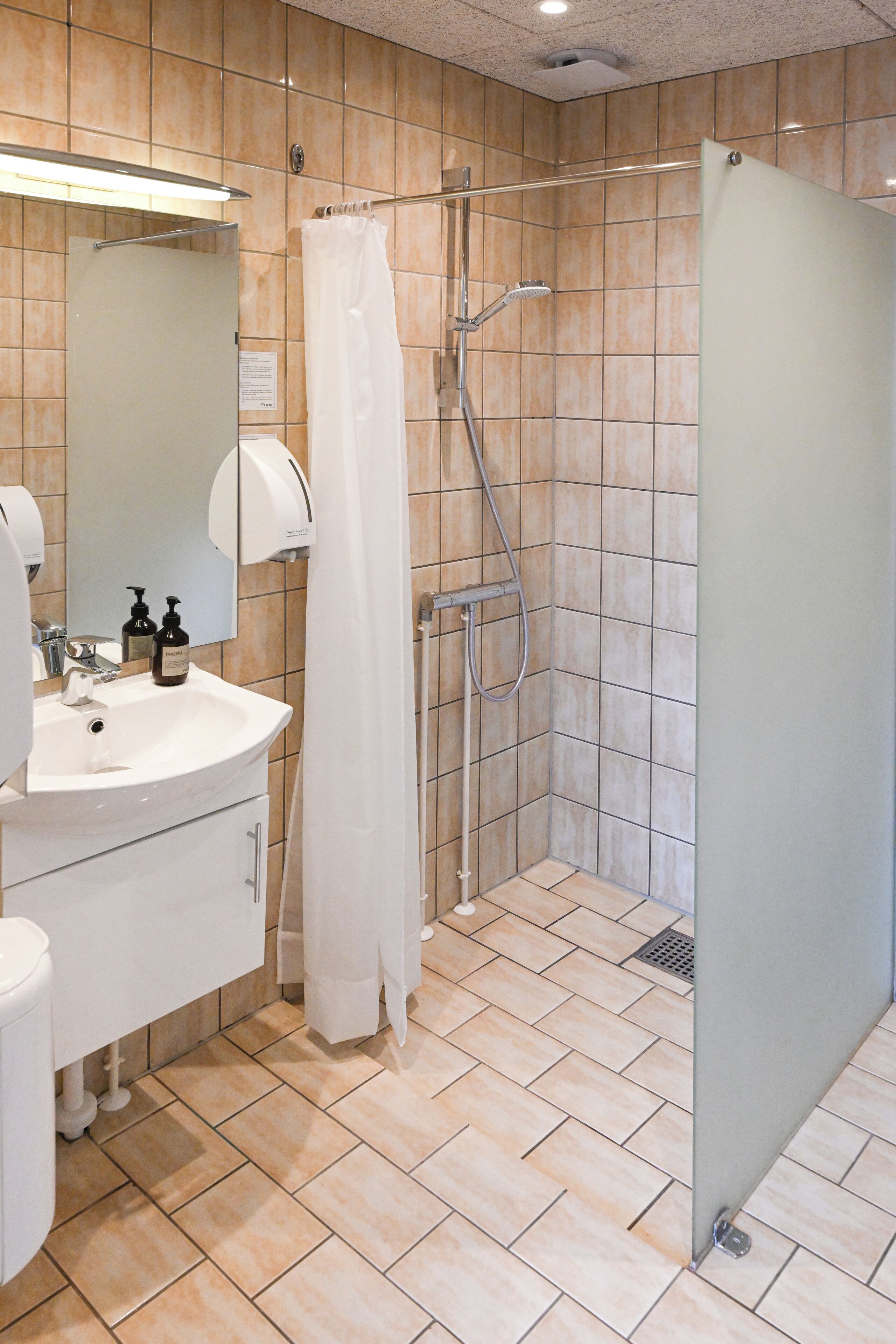 A bathroom with a sink, mirror, and shower area.