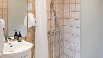 A bathroom with a sink, mirror, and shower area.